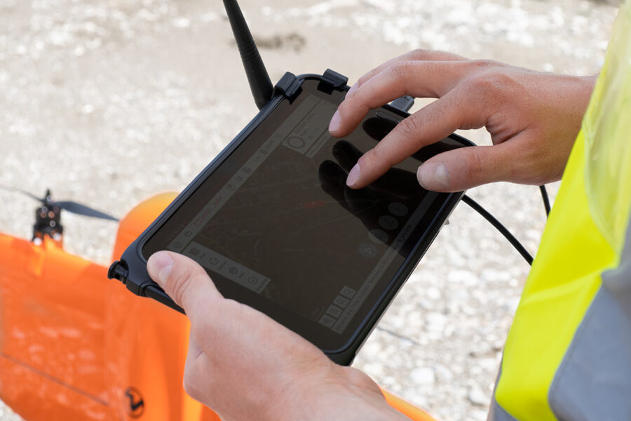 Drone WingtraRAY a voar sobre campo agrícola durante missão de mapeamento topográfico.